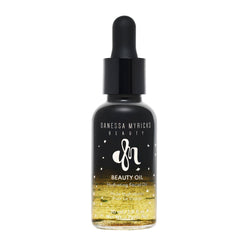 A studio product shot of a black and clear gradient glass dropper bottle containing a golden-flecked liquid formula. Text reads: Beauty Oil Hydrating Facial Oil